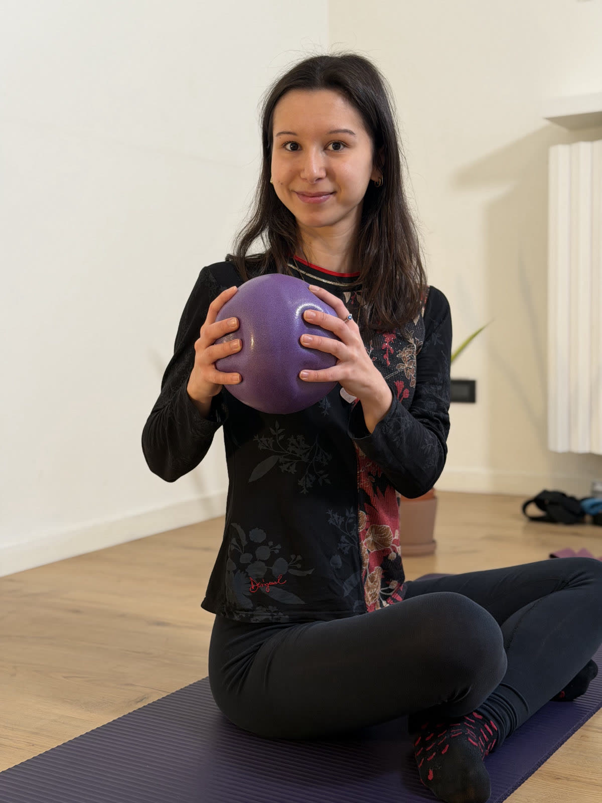 Insegnante seduta con la soft-ball durante una lezione di Pilates Matwork in sala a Mompiano