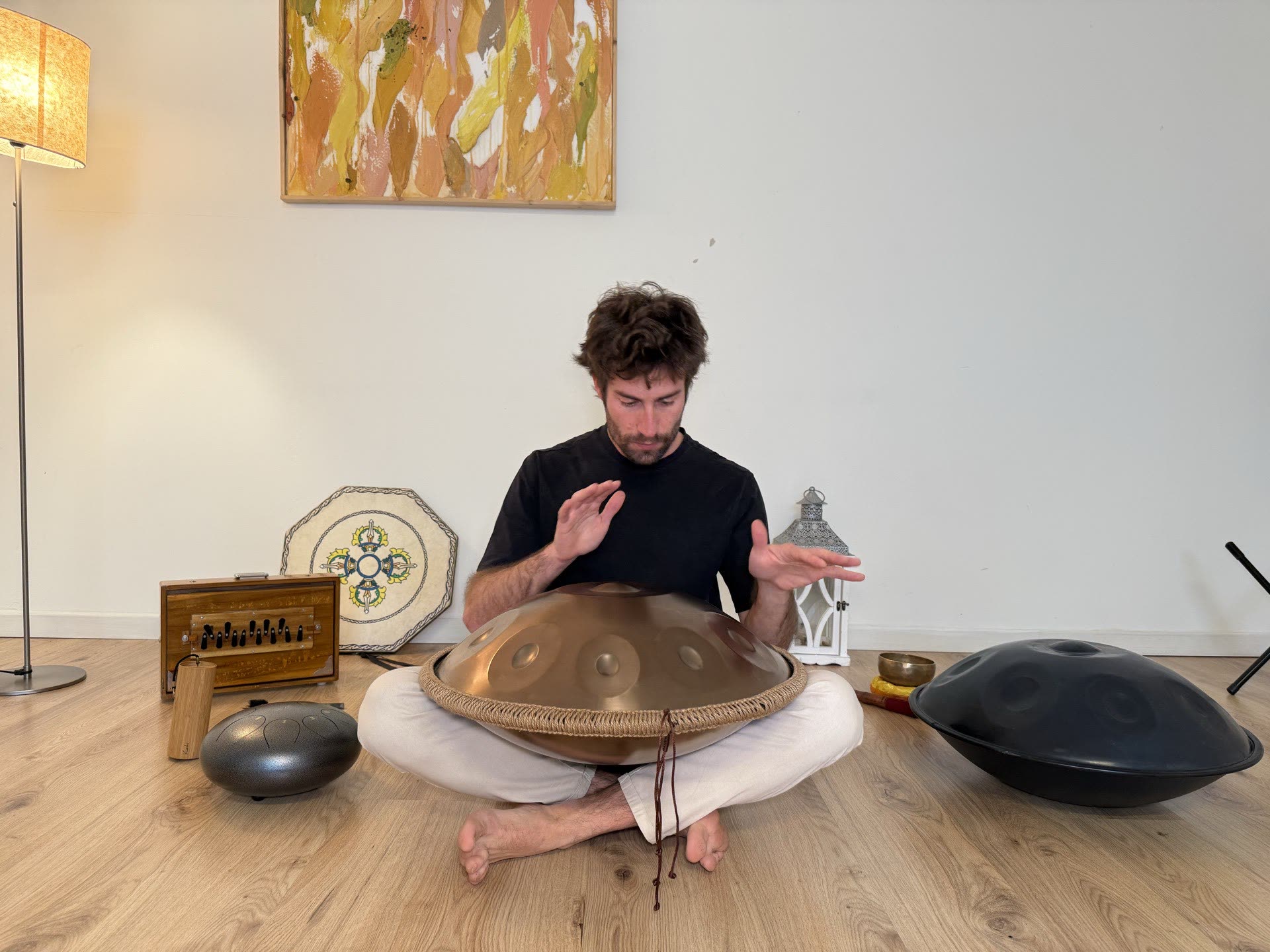 Michele Frosio suona l'handpan seduto a terra, tra gli strumenti del bagno sonoro